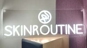 Включённый неоновый логотип с тёплым белым свечением при включённом освещении помещения