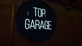 Световая неоновая вывеска Top Garage на черном акриле, вид слева в три четверти