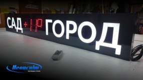 Композитний лайтбокс з вуличним LED-годинником на столі в майстерні, вигляд справа в три чверті