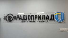 Інтер’єрна несвітлова вивіска підприємства з прозорого акрилу з чорними літерами та логотипами, вид прямо