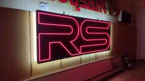 Неоновий логотип RS для автосалону, вигляд зліва під кутом три чверті під час тестування у шоу-румі