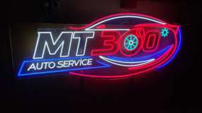 Неоновий LED логотип автосервісу на прозорому акрилі, вигляд під кутом зліва, чотири кольори світіння