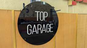Неонова вивіска Top Garage на чорному акрилі, вигляд зліва під кутом, у вимкненому стані