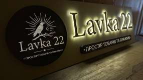 Рекламна вивіска LAVKA 22 у темній майстерні, вигляд зліва під кутом, контражурне підсвічування плоских літер та комбіновані лайтбокси